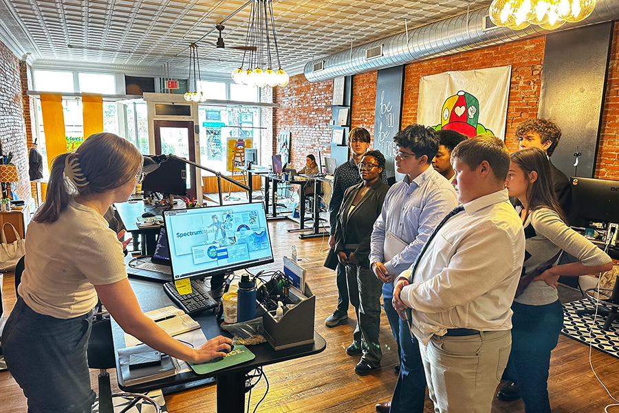 A woman is showing several CAPS students a computer screen of a recent project she created inside the Fierce Creative Agency Studio