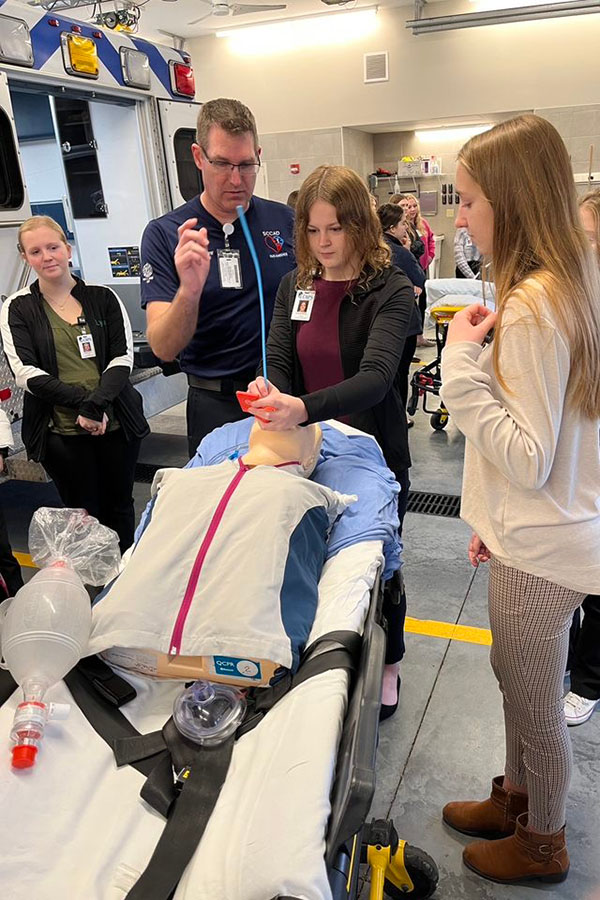 Several CAPS students watch as a CAPS student learns how to intubate a patient