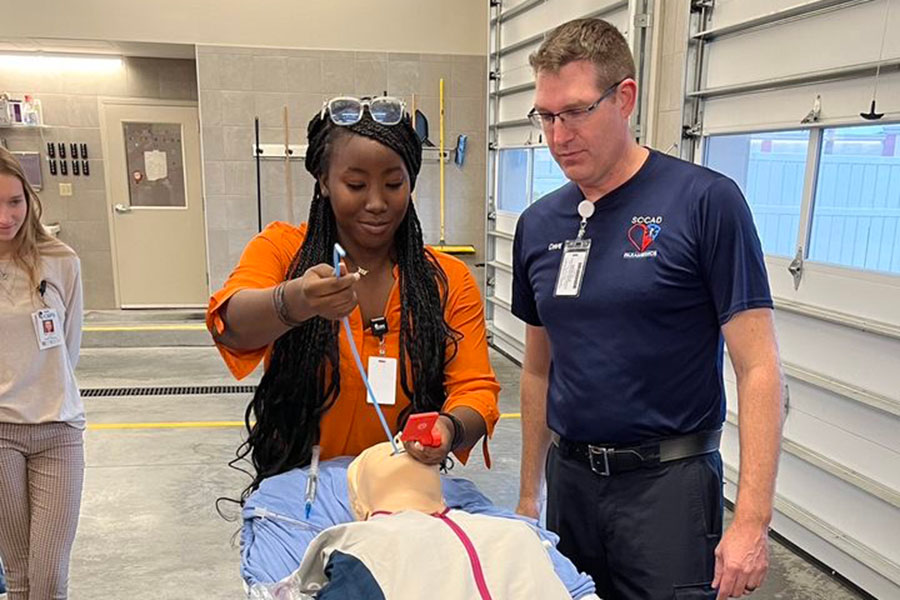 A CAPS students is learning from a SCCAD employee how to intubate a patient