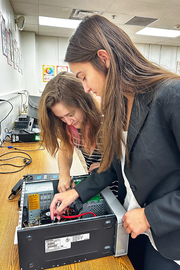 Two CAPS students working on the internal of a computer